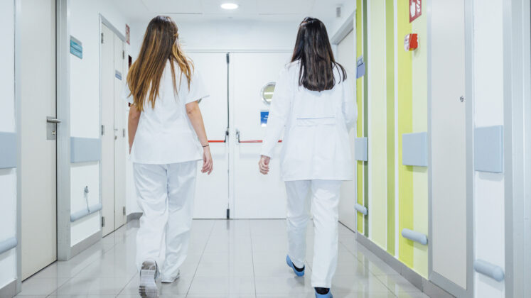 Two hospital staff walking towards fire door