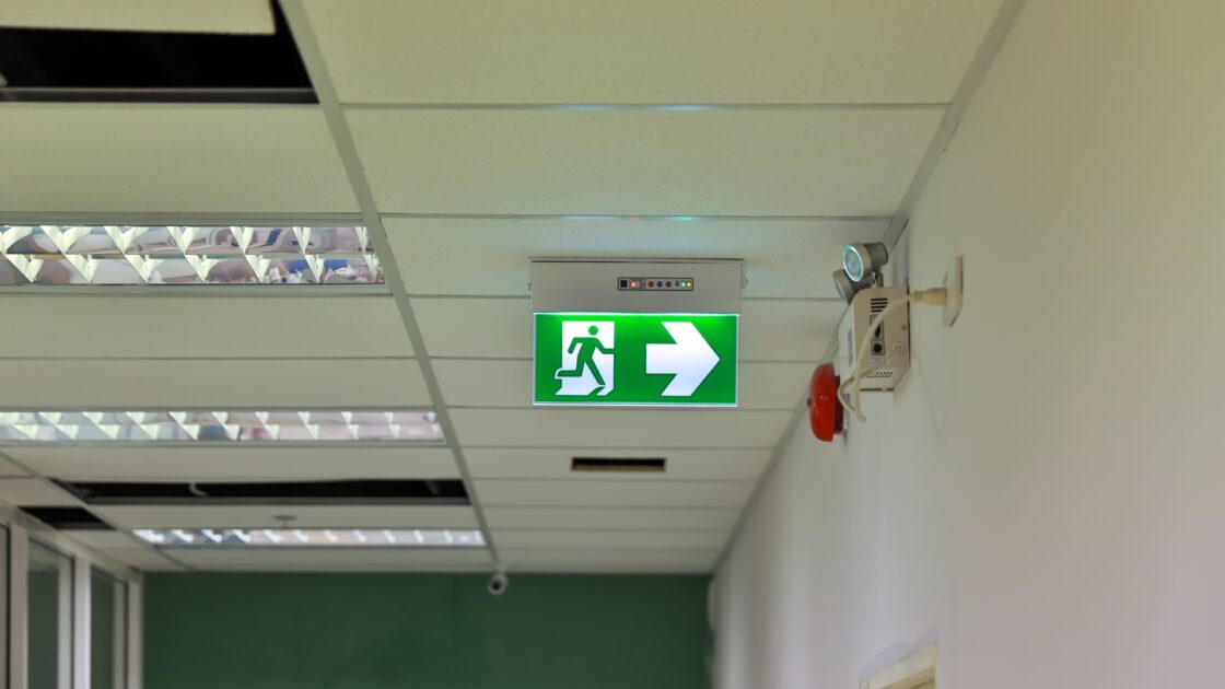 Illuminated Fire Escape sign in communial corridor of a tower block