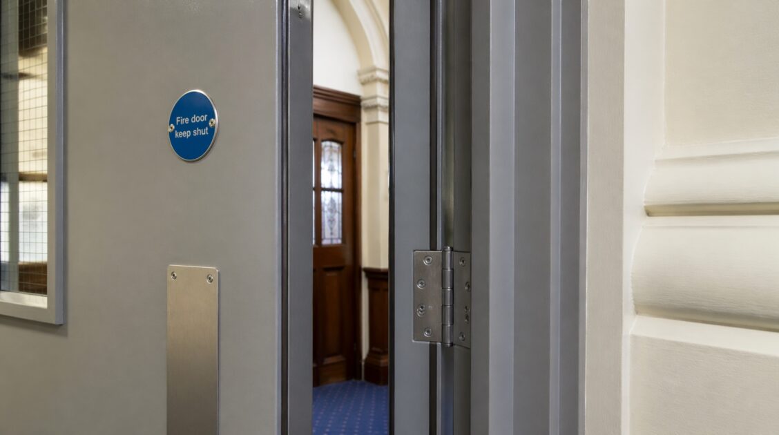 Close up of fire door with intumescent strips and hinges showing proper installation for fire safety.